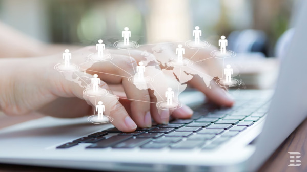 Close-up of hands typing on a laptop with a world map